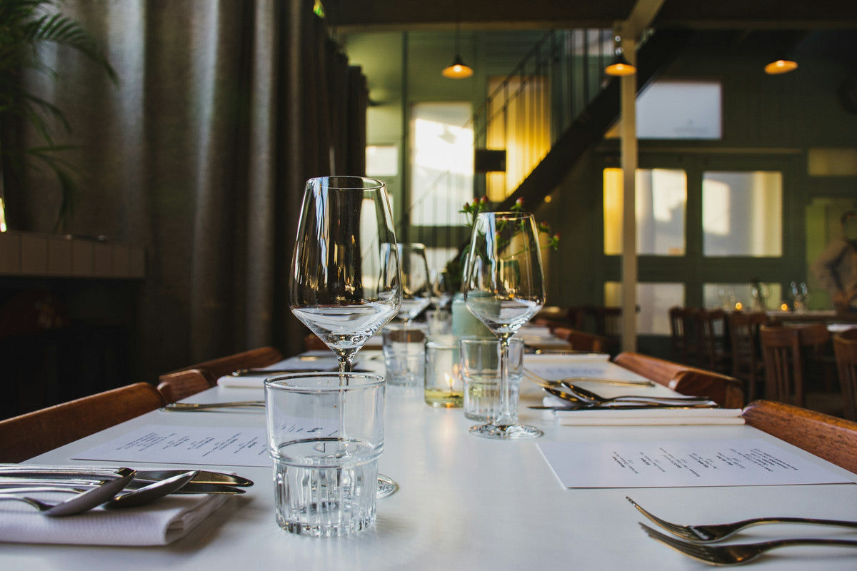 Table dressée avec verres à vin, couverts et nappe blanche